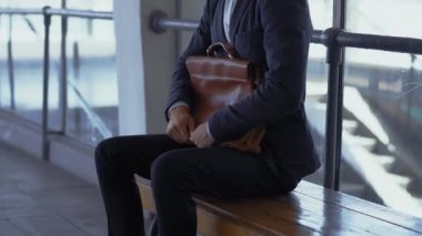 Freelancer çalışanı evrak çantasını koruyor metro istasyonunda bankta oturuyor, treninin ofise ya da müşterilerine ulaşmasını bekliyor. Evrak çantalı bir erkek işadamı işe gider. Prores 422