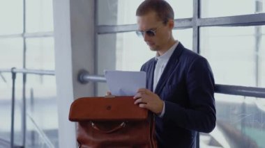 Takım elbiseli serbest çalışan biri evrak çantasındaki belgeleri kontrol ediyor metro istasyonunda bankta oturuyor, trende bekliyor. Metro 'da evrak çantası olan bir erkek işadamı. Kapatın. Prores 422