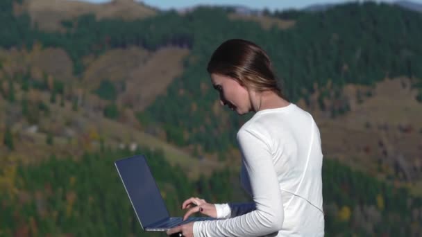 Mladá žena na volné noze s otevřeným laptopem, sedící na vrcholu hory v Karpatech. Freelancer je práce na dálku pomocí nových satelitních technologií. Hory Karpat. Prores 422 — Stock video