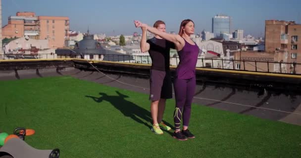 Sportliches Paar, Mann und Frau in Sportbekleidung, beim Stretching auf dem Dach eines Gebäudes, urbaner Hintergrund. Prores 422 — Stockvideo