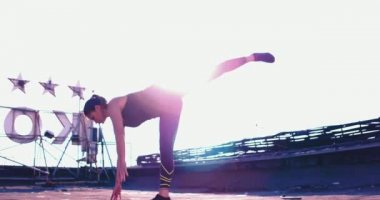 Kız dışarıda askıda geriniyor. Bir bacağını kaldırıyor ve dengesini koruyor.