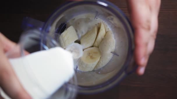 Mleko wlewa się do miksera, mieszając z bananami. Mieszadło miesza owoce z mlekiem. Koncepcja shake 'a mlecznego. Zwolnij trochę. Wysokiej jakości materiał filmowy FullHD — Wideo stockowe