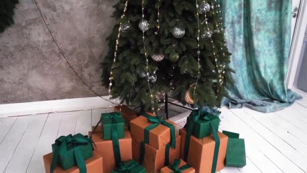 Revisión del interior de Año Nuevo. Los regalos de Año Nuevo en cajas naranjas se encuentran debajo de un árbol de Navidad decorado. La cámara se mueve de abajo hacia arriba. Disparo de Navidad. Imágenes FullHD de alta calidad — Vídeos de Stock