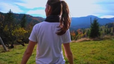 Genç turist kız, dağların arkasındaki düzlükte dans ediyor. Karpatlar 'a sonbahar yürüyüşü. Yüksek kalite 4k görüntü