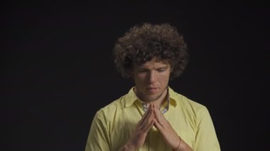 Adam ellerini kavuşturdu ve gözlerini kapadı. Umut ediyor ve tahmin ediyor. Stüdyoda izole bir arka plan var. Yüksek kalite 4k görüntü