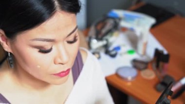 Orta yaşlı bir kadın yüzüne bir kapatıcı koyar ve parmaklarıyla siler. Bir ayna tutuyor ve makyaj yapıyor. Orta yaşlı bir kadın yüzüne bir kapatıcı koyar ve yüzüne bir leke sürer.