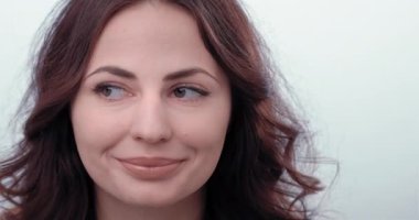 Genç kadın yan yana bakar ve kaşlarını kaldırır. Sonra kameraya baktı ve kaşlarını bükerek gülümsedi.. 