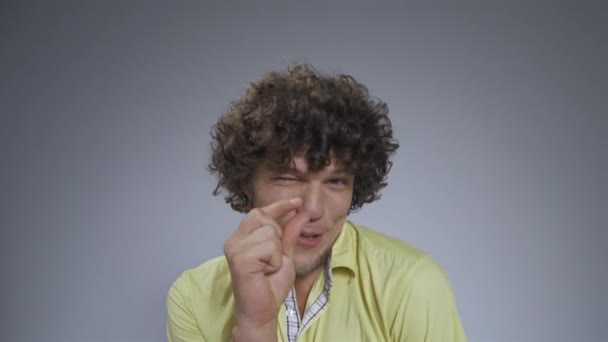 Guy in the studio shows a small size gesture. Curly man shows off small size with his fingers. High quality — Stock Video