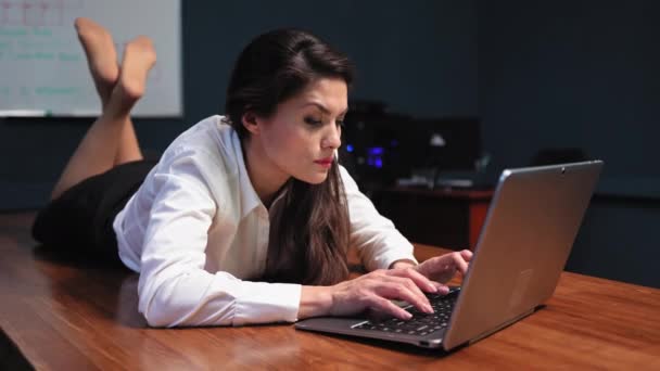 Wanita berbaring di meja di kantor dan bekerja di belakang laptop. Istirahat dalam konsep kantor. Wanita bisnis di meja dengan komputer. Rekaman 4k berkualitas tinggi — Stok Video