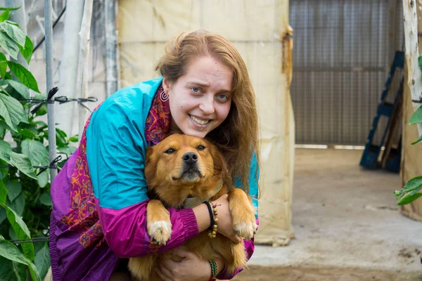 Kahverengi köpeğe sarılan bir kadın.