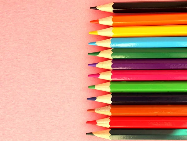 Színes ceruzák rózsaszín háttérrel. Sok különböző színű ceruza. Színes ceruza. Ceruzák élesek. A ceruzák jobbra vannak. Gyönyörű háttér. Közelkép. Másold a helyet. Háttér. Lapos fektetés Stock Fotó