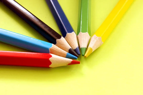 Semicircle of colored pencils on a yellow background. Lots of different colored pencils. Colored pencil. Pencils are sharp. Pencils lie in top left corner. Close-up. Copy space. Background. Flat lay.