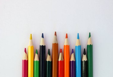 Beyaz arka planda, sarsıcı bir sırayla renkli kalemler. Bir sürü farklı renkli kalem. Renkli kalem. Kalemler keskindir. Yakın plan. Uzayı kopyala Geçmişi. Düz yatıyordu.