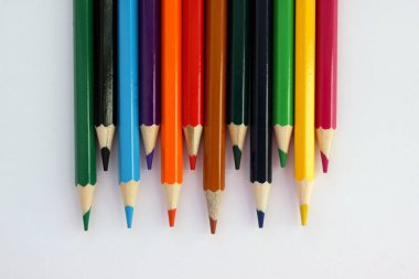 Beyaz arka planda, sarsıcı bir sırayla renkli kalemler. Bir sürü farklı renkli kalem. Renkli kalem. Kalemler keskindir. Kalemler üstte. Yakın plan. Uzayı kopyala Geçmişi. Düz yatıyordu