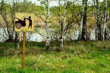 Sembol işareti çöpü de yanında götür. Tabela gölün kıyısına asıldı. Ekoloji. Kirlilik. Tabela solda..