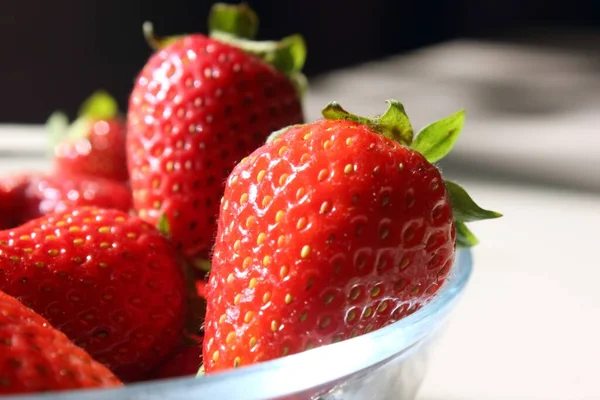 Verse rijpe heerlijke aardbeien in een glazen bord op de tafel.Stapel rode aardbeien op een bord close-up. Eten. Vitaminen. Boerderij. Een deel van een bord met aardbeien. Kopieer ruimte voor tekst — Stockfoto