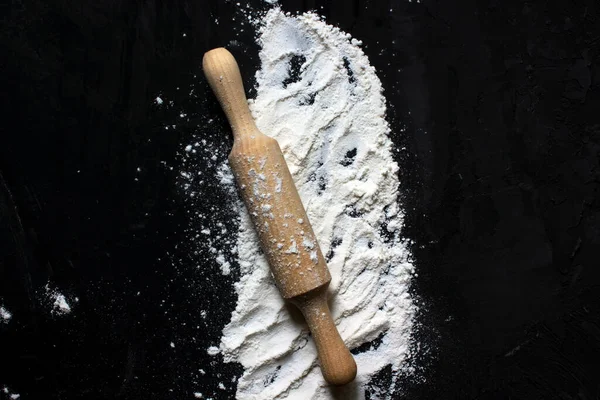 Un kaplı siyah bir yüzeyde hamuru yuvarlamak için merdane. Merkezde yer alıyor. Yukarıdan manzara. Pişirme. Ev yapımı yemek. Metin için alanı kopyala