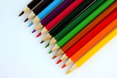 Beyaz arka planda renkli kalemler. Bir sürü farklı renkli kalem. Renkli kalem. Kalemler keskindir. Kalemler sağ üst köşeye çapraz yerleştirilmiş. Yakın plan. Uzayı kopyala Geçmişi. Düz Yatay