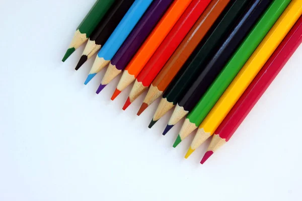 Colored pencils on white background. Many different colored pencils. Color pencil. Pencils are sharp. Pencils placed diagonally in the upper-right corner. Close-up. Copy space. Background. Flatlay.