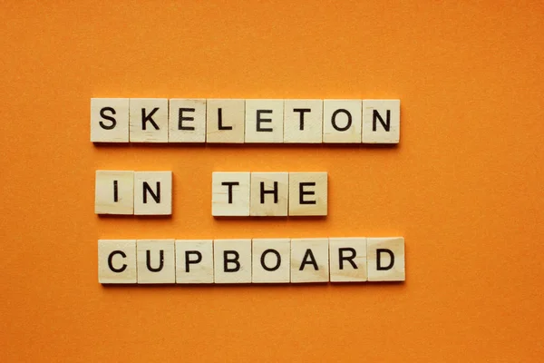 Words Skeleton in the Cupboard. Wooden blocks with an inscription on an orange background. Bulletin board. The concept of the holiday is Halloween. The view from the top. Copy space — Stock Photo, Image