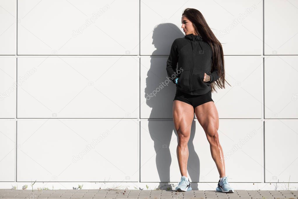 Sexy athletic woman with big quads. Muscular girl posing outdoor, muscular legs