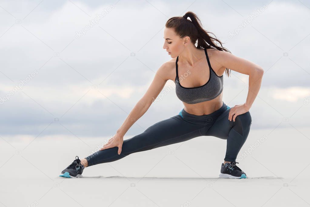 Fitness woman doing lunges exercises for leg muscle workout training, outdoor. Sporty girl doing stretching exercise