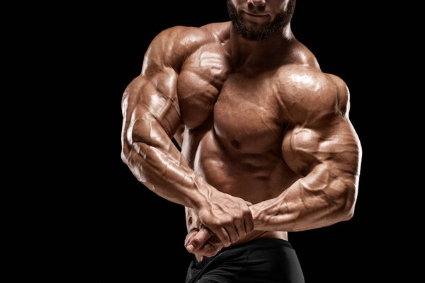 Muscular man showing muscles and biceps isolated on the black background. Bodybuilder male naked torso abs
