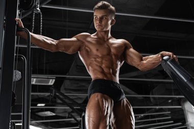 Spor salonunda kaslı adam egzersizi, güçlü erkek çıplak vücut kasları.