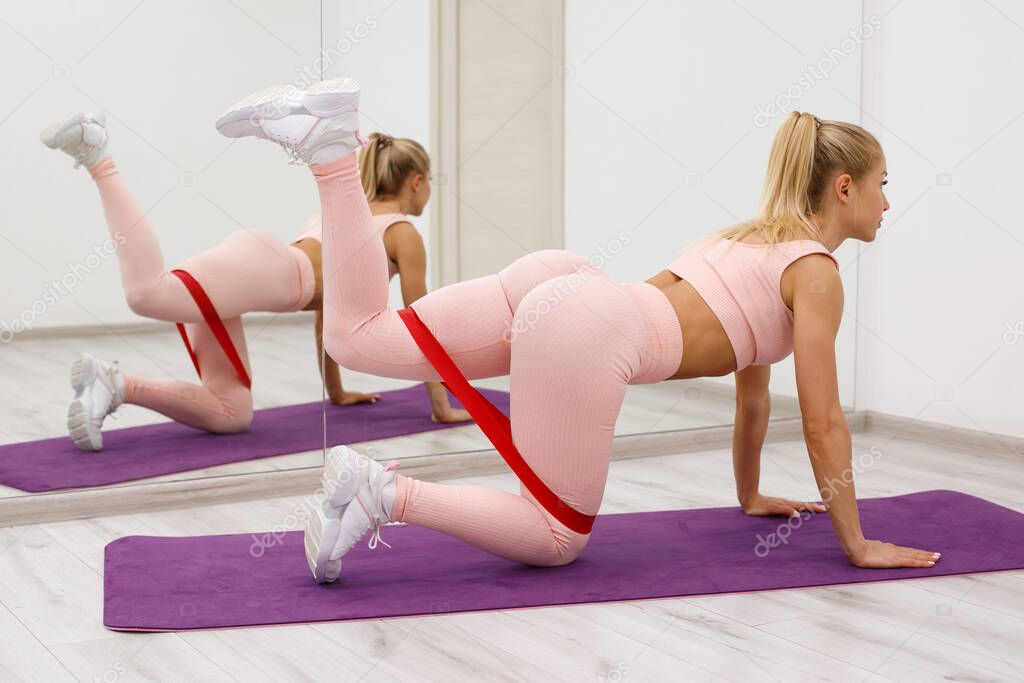 Fitness woman doing kickback exercise for glute with resistance band. Athletic girl working out