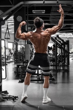 Spor salonundaki kaslı adam sırt kaslarını dikiz aynasından gösteriyor. Güçlü erkek çıplak gövde
