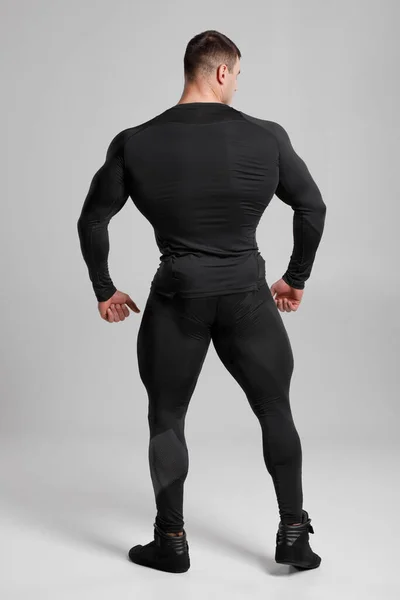 Homem Muscular Compressão Preta Sportswear Visão Traseira Sobre Fundo Cinza — Fotografia de Stock