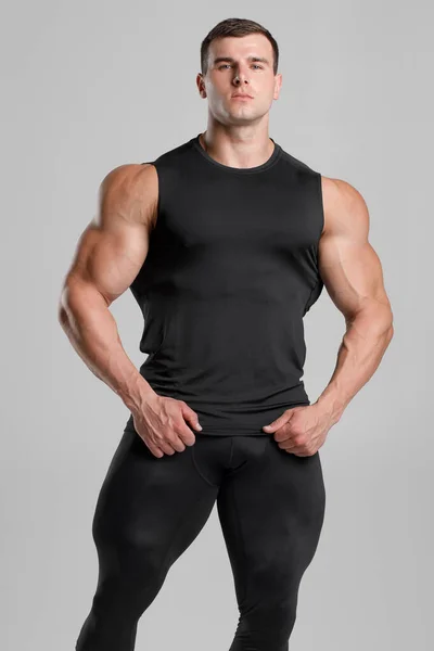 Мускулистый Человек Черной Компрессионной Спортивной Одежде Сером Фоне — стоковое фото