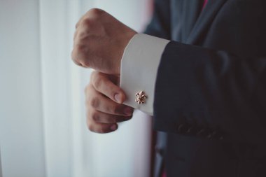 Pencere kenarındaki beyaz gömlekli adam. Kol düğmeleri.