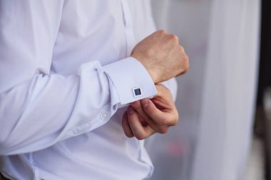 Pencere kenarındaki beyaz gömlekli adam. Kol düğmeleri.