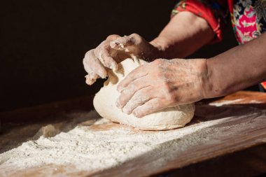 Üst düzey kadın elleriyle mutfağındaki bir masaya hamur yoğurdu.