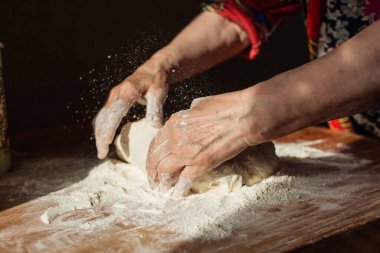 Üst düzey kadın elleriyle mutfağındaki bir masaya hamur yoğurdu.