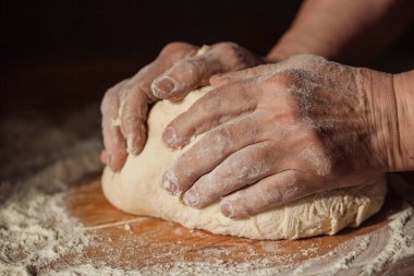Üst düzey kadın elleriyle mutfağındaki bir masaya hamur yoğurdu.