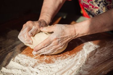 Üst düzey kadın elleriyle mutfağındaki bir masaya hamur yoğurdu.