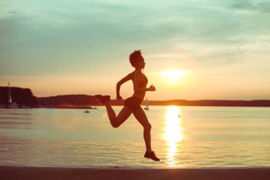 Çekici genç Afrikalı atlet gün batımında ya da plaj boyunca gün doğumunda koşuyor.