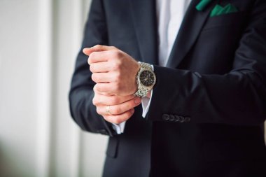 Penceredeki beyaz gömlekli adam saat takıyor.