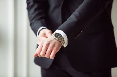 Penceredeki beyaz gömlekli adam saat takıyor.