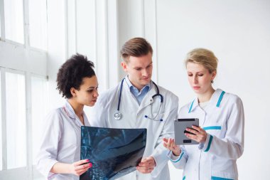 Sağlık hizmetleri, sağlık: Bir klinik veya hastanede çok ırklı doktorlar röntgenleri tartışıyor ve inceliyor