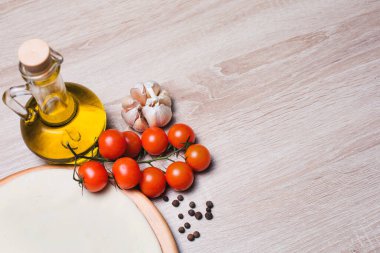 Tahta üzerinde pizza ve kiraz domatesleri, zeytinyağı, baharatlar, sarımsak..