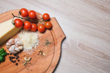 Tahtada parmesan peyniri ve kiraz domatesleri, zeytin yağı, baharatlar.