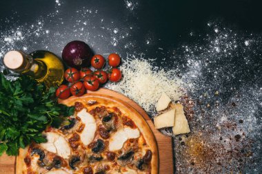 Pepperoni, domates, mozzarella, sarımsak ve siyah arka planda maydanoz şeklinde pizza kalbi.