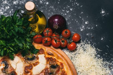 Pepperoni, domates, mozzarella, sarımsak ve siyah arka planda maydanoz şeklinde pizza kalbi.