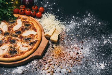 Pepperoni, domates, mozzarella, sarımsak ve siyah arka planda maydanoz şeklinde pizza kalbi.