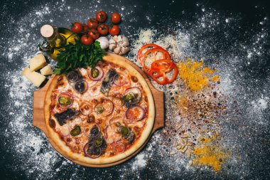 Etli lezzetli pizza, kırmızı biber, siyah arka planda soğan.