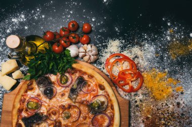 Etli lezzetli pizza, kırmızı biber, siyah arka planda soğan.