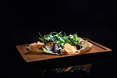 Tahtasında sıcak somon olan vejetaryen salatası.